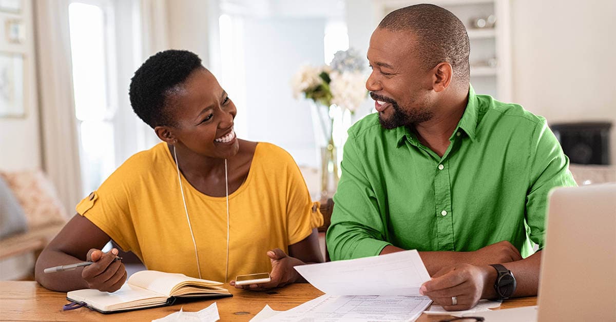 A family sits at a computer planning out their 50/30/20 budget with Huntington Bank.