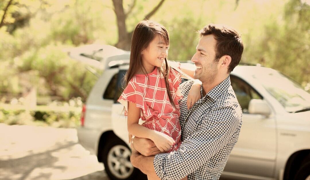 Man holding girl by car